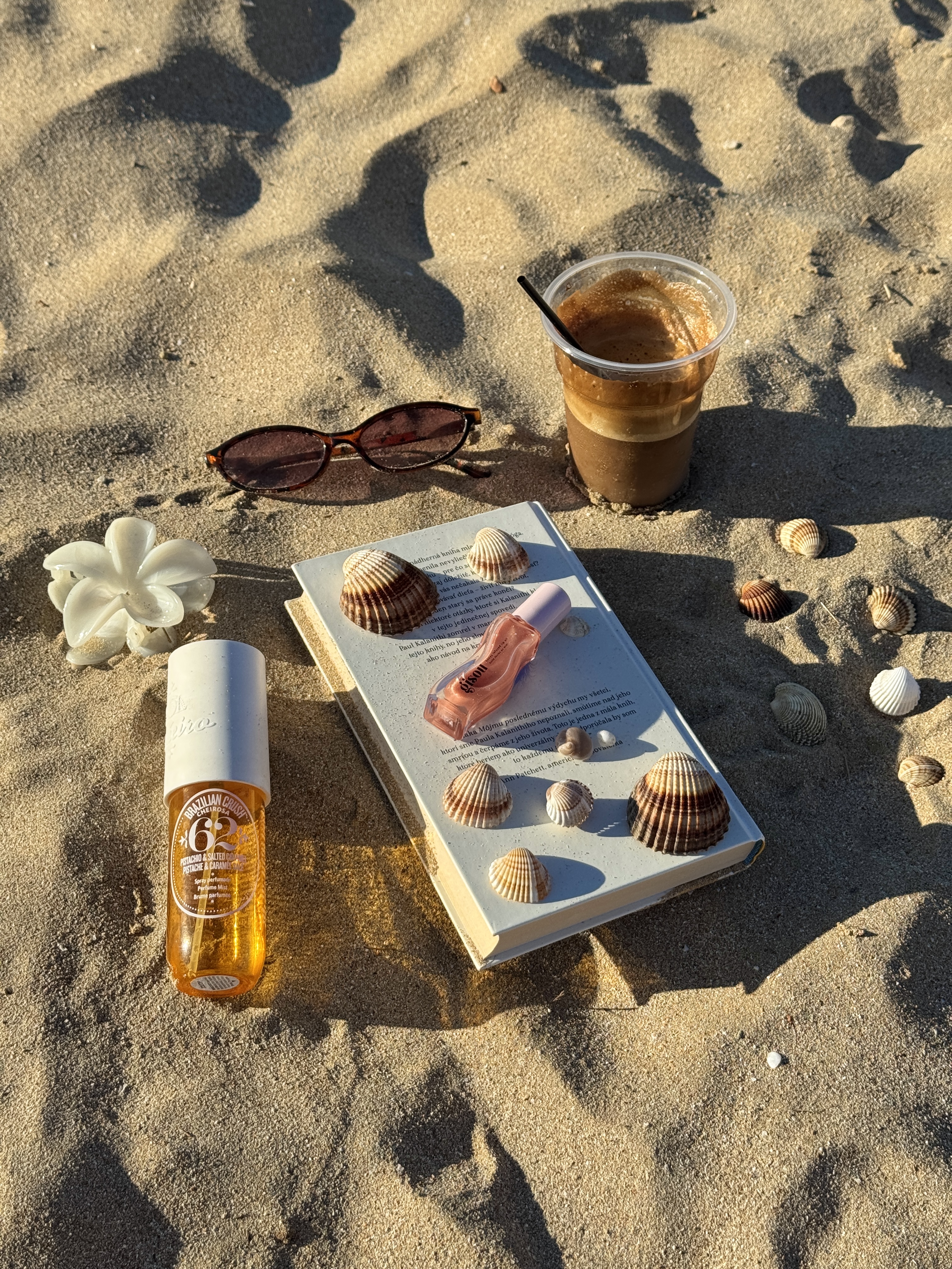 Beach still life with coffee, perfume, and book.